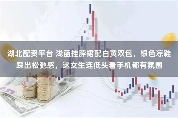 湖北配资平台 浅蓝挂脖裙配白黄双包，银色凉鞋踩出松弛感，这女生连低头看手机都有氛围